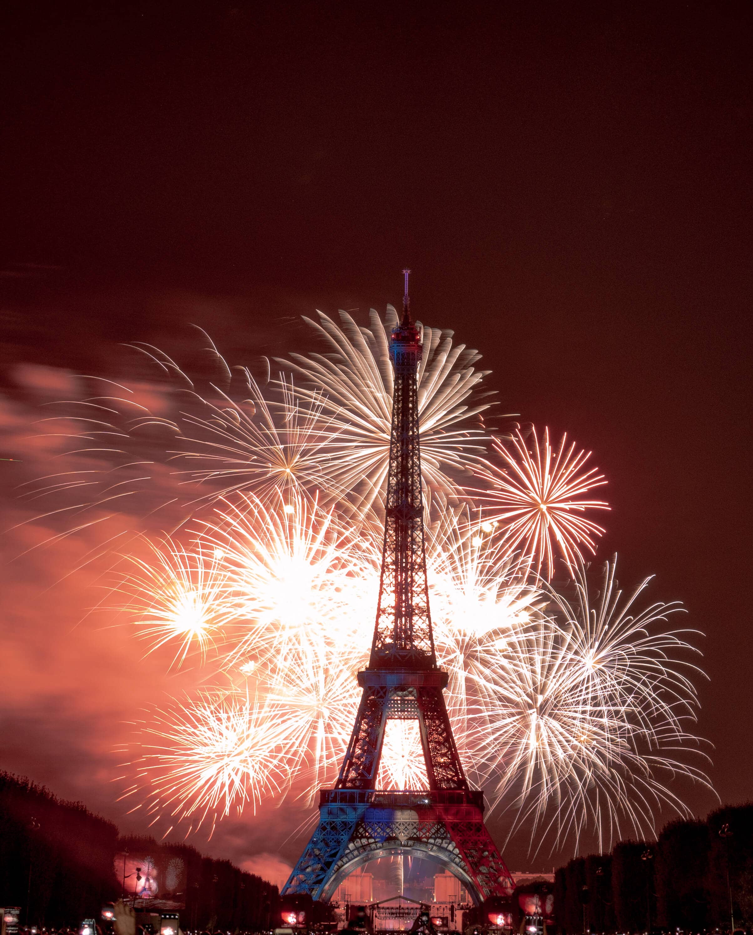 Feux d'artifices du 14 Juillet à Paris depuis le Champ de Mars. La tour Eiffel éclairée en bleu blanc rouge.